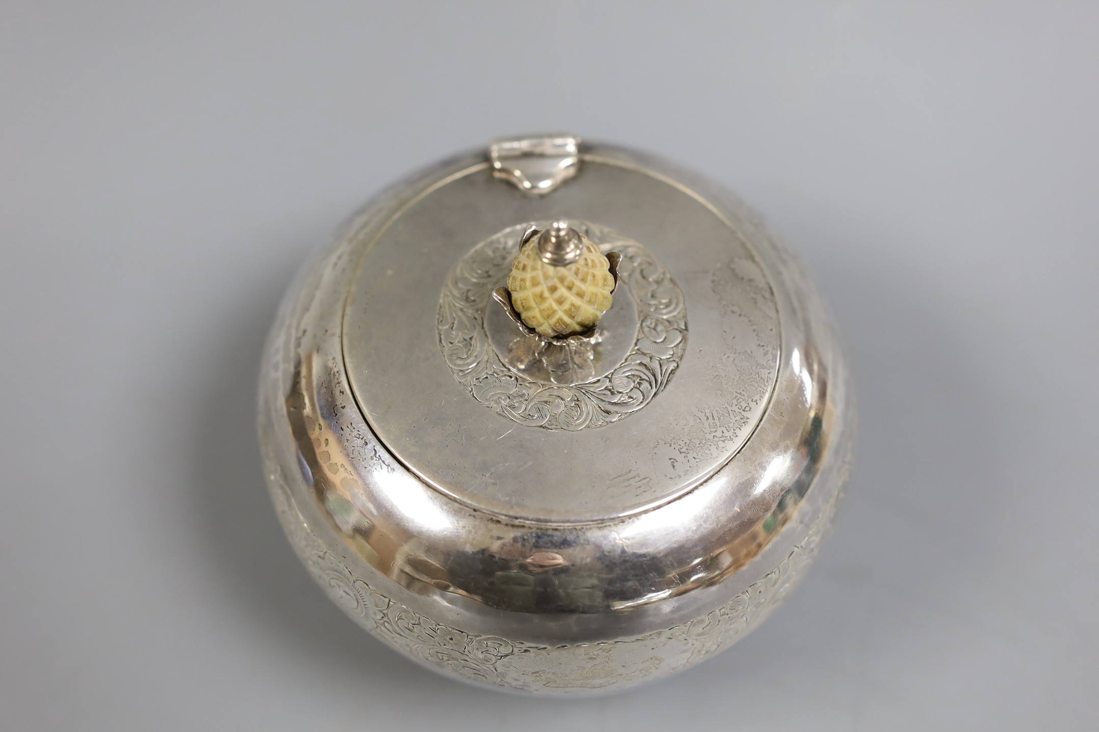 A George V engraved silver globular tea caddy, with carved stained wooden pineapple shaped knop, Goldsmiths & Silversmiths Co Ltd, London, 1920, height 11.3cm, gross weight 12oz.